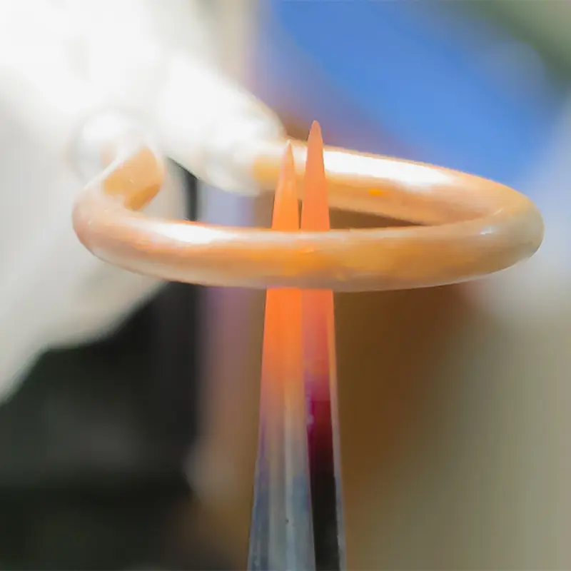 Induktionsspule erhitzt eine metallene Pinzette durch Induktionserwärmung