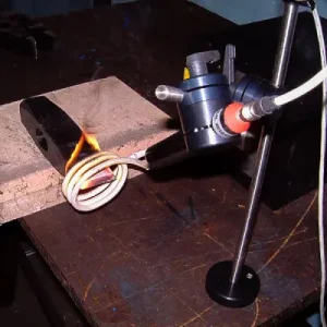 Ein Beilkinge wird durch Induktionserwärmung auf die benötigte Temperatur für die Härtung erhitzt. Eine Spule umgibt das Werkstück, das gleichmäßig erwärmt wird.